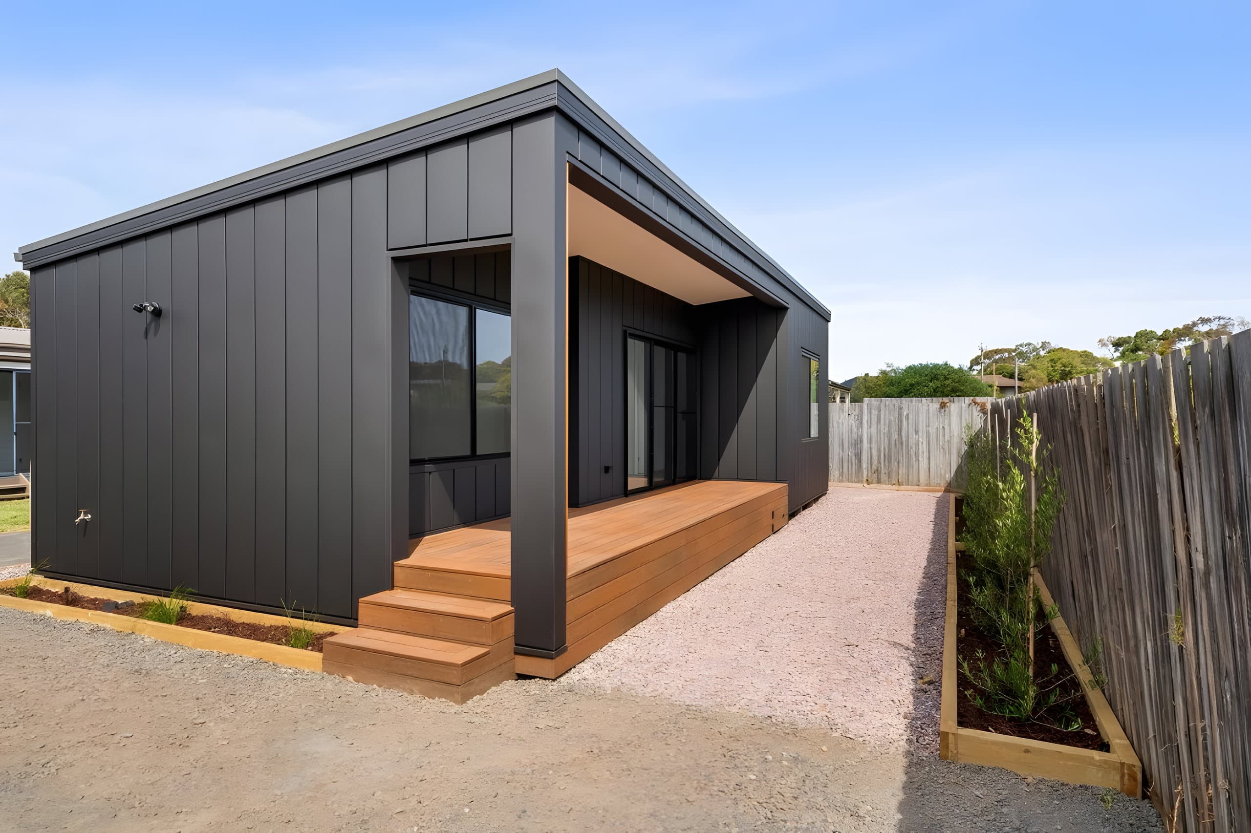 Custom studio with dark cladding and timber deck, Warrnambool
